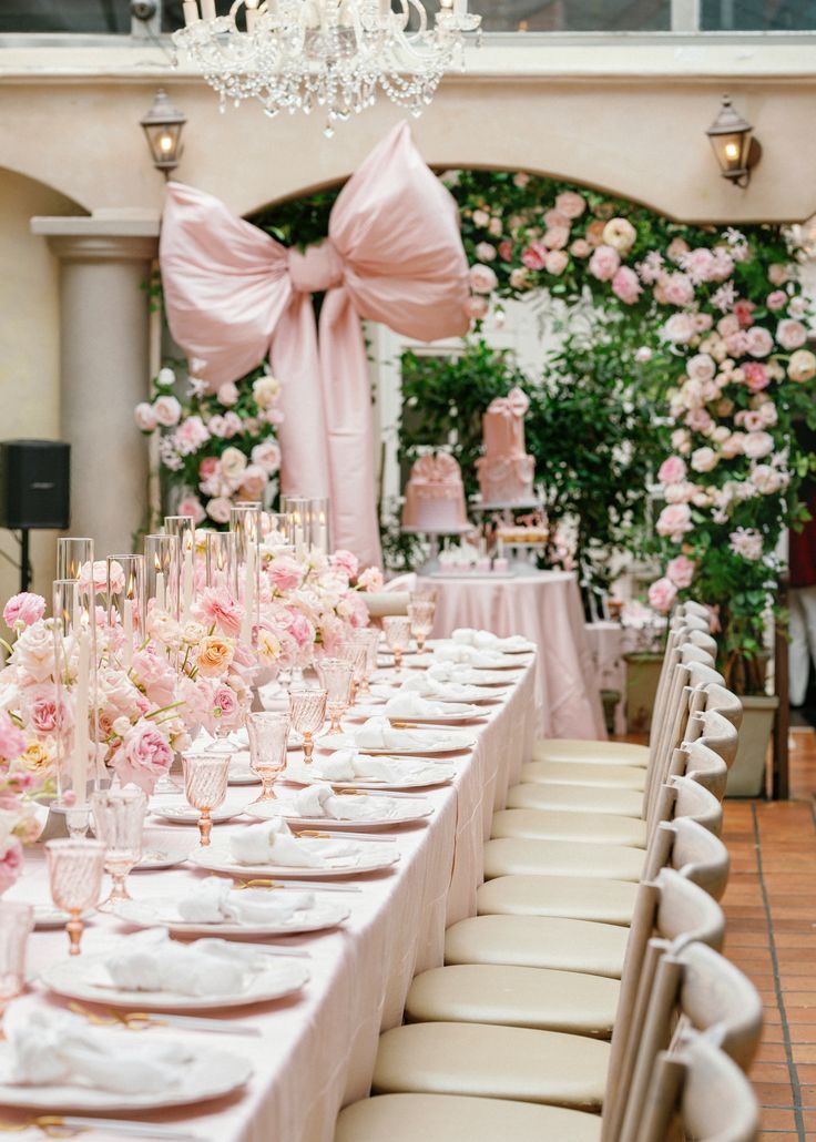 a long table is set with pink flowers and champagne glasses for an elegant wedding reception