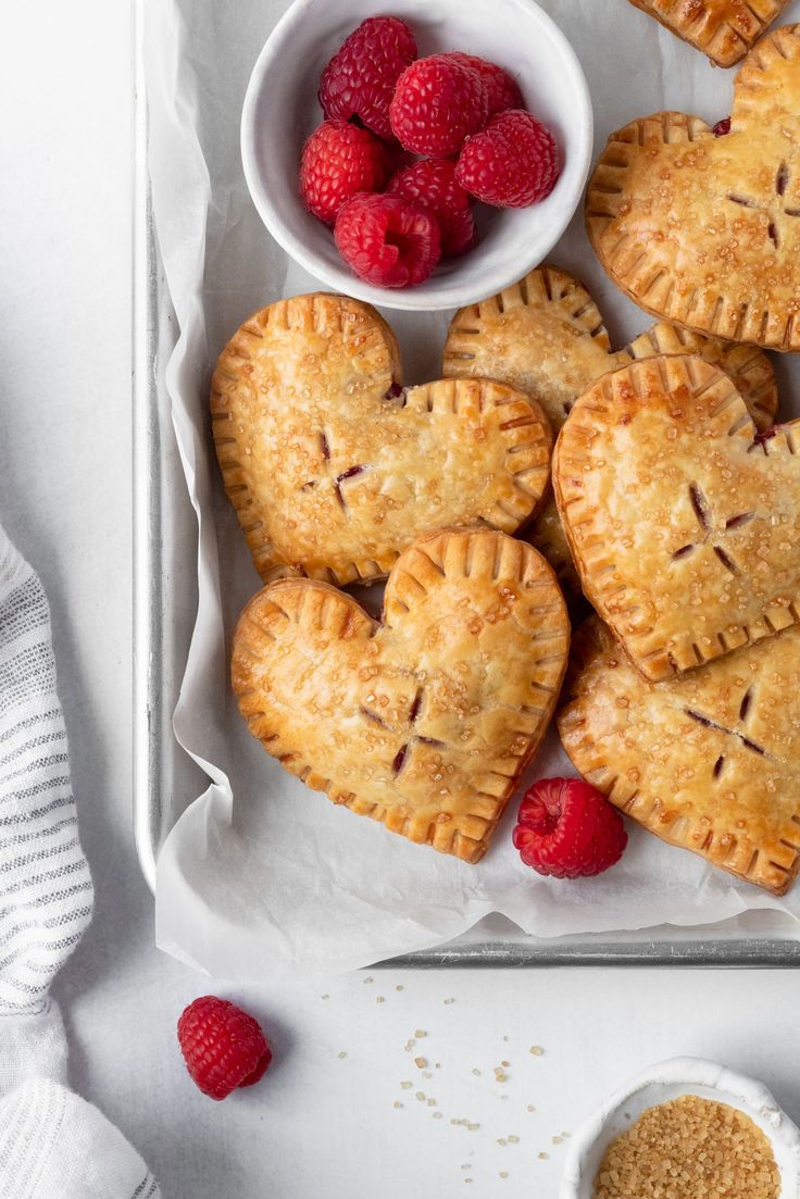 raspberry hand pies on a tray with fresh raspberries next to them