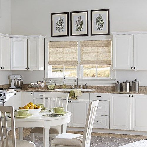 a kitchen with white cabinets and chairs around a small round table in front of the window