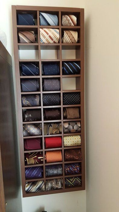 a wooden shelf filled with ties next to a wall mounted cabinet full of different types of ties