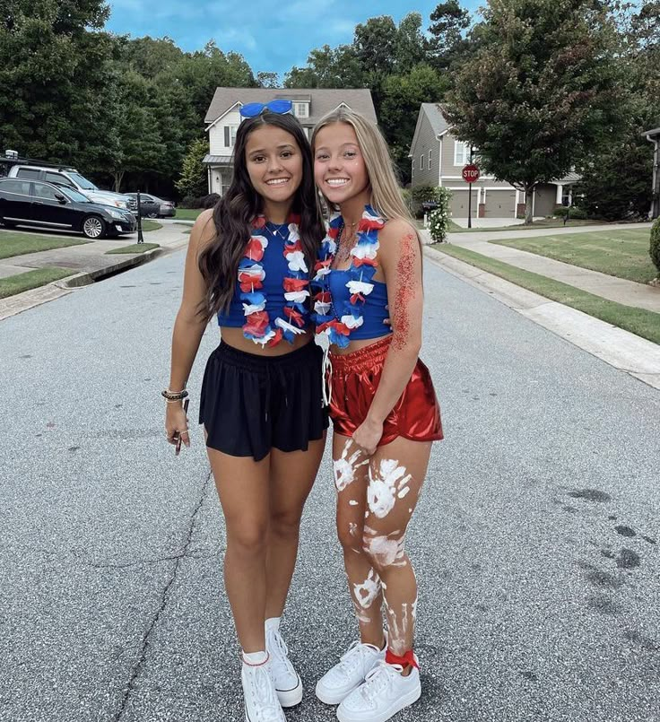 two young women standing next to each other in front of a street with houses and trees