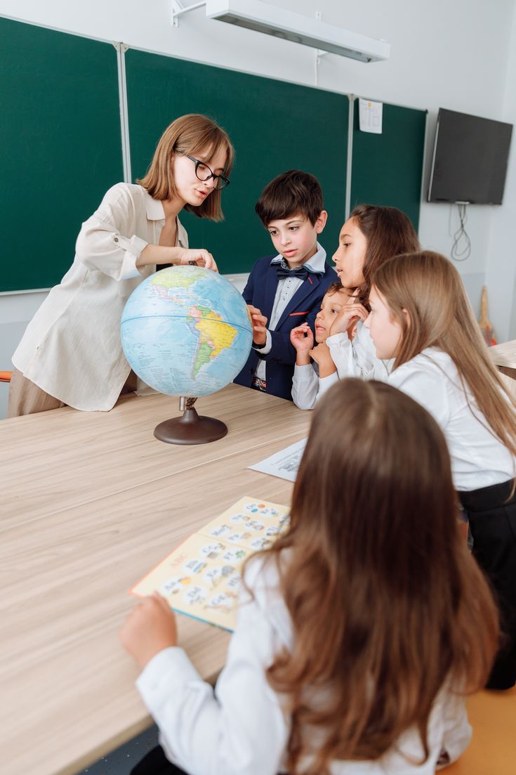 several children are sitting at a table with a globe in front of them and one child is looking at it