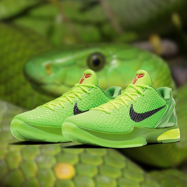 a pair of green nike sneakers on top of a snake skin surface with an eyeball in the background