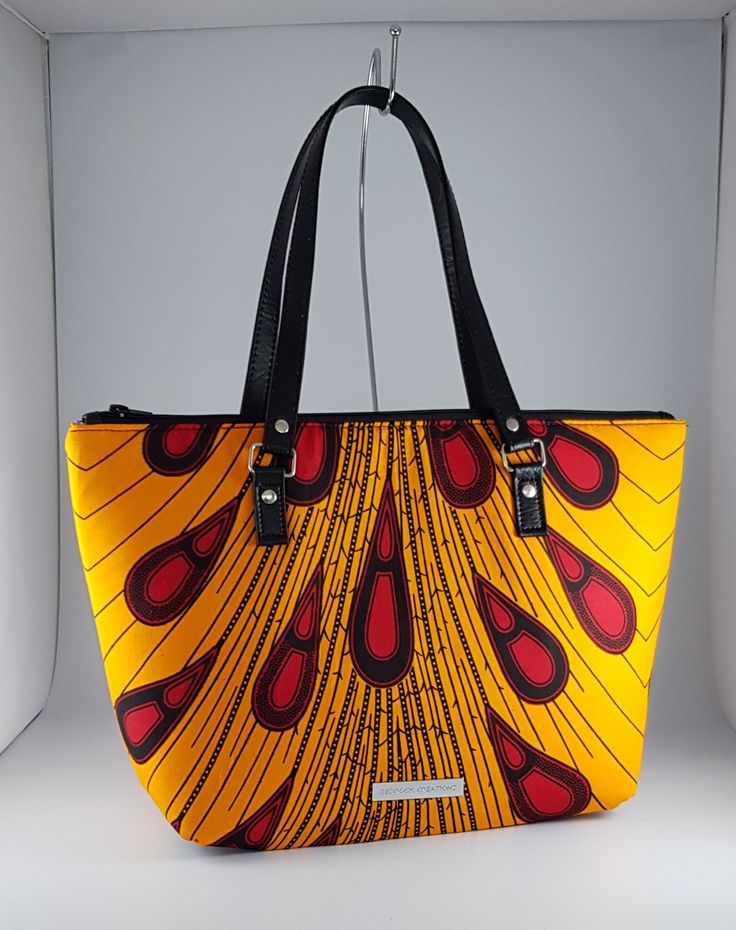 "\"Bag description:  This lovely bag is a perfect size for any occasion, with ample room for all your essentials when shopping, going to the office or on an evening out. The peacock design in yellow and wine also look great against a little black dress brightening the autumn day. This tote bag is a combination of Ankara African fabric and faux leather, fully lined waterproof canvas fabrics. The handles are long enough to fit comfortably on the shoulder or held by hand. Internally, this bag is fully lined with waterproof canvas and zippered pocket which fits your phone or other valuables. This bag is closed with a durable zip. Bag Style: Tote Fabric: African Wax Print Fabric - Ankara yellow and wine print fabric. 100% Cotton Lining: Waterproof canvas Hardware: Chrome  Handles: 24 inches in Yellow Satchel With Top Carry Handle For On-the-go, Yellow Satchel Bag For On-the-go, Multicolor Top Handle Bag With Zipper Closure, Yellow Large Capacity Bag For On-the-go, Yellow Top Handle Bucket Bag For Travel, Trendy Yellow Shoulder Bag, Trendy Yellow Satchel For Shopping, Yellow Rectangular Bag With Top Carry Handle, Trendy Yellow Double Handle Bag