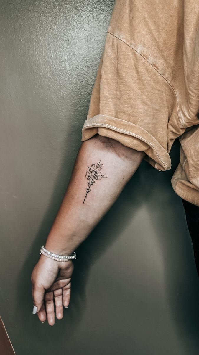 a woman's arm with a small flower tattoo on the left side of her hand