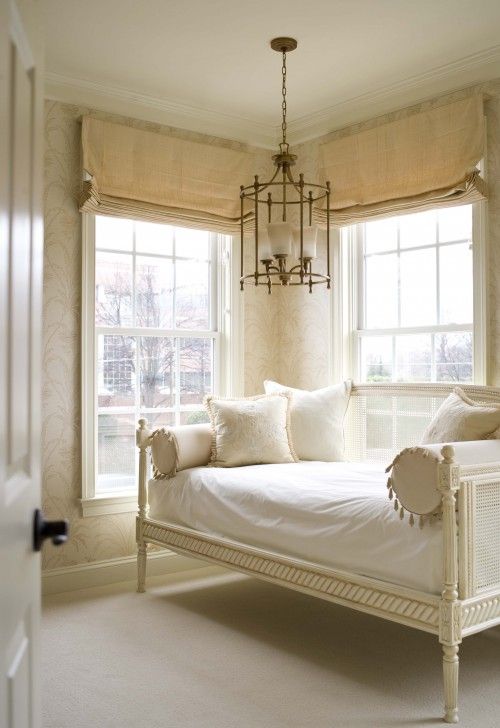 a white day bed sitting next to two windows in a room with carpeted floors