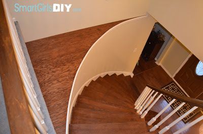 an aerial view of a spiral staircase in a home with hardwood floors and white railings