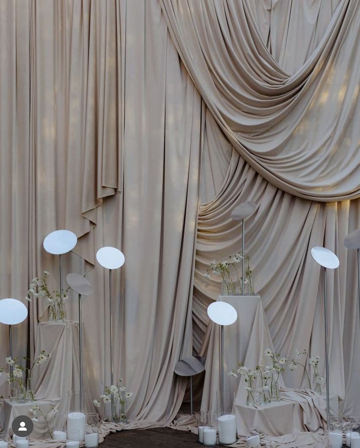 a room filled with lots of white vases next to a wall covered in drapes