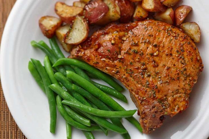 a white plate topped with meat, potatoes and green beans