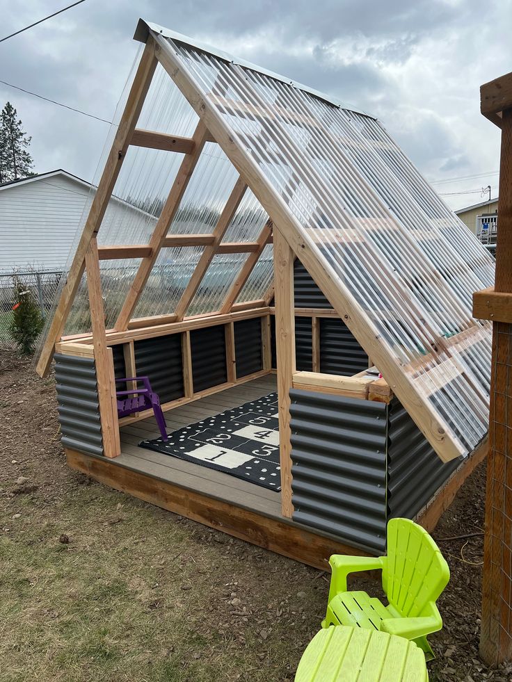 a small house made out of metal and wood with a green lawn chair next to it