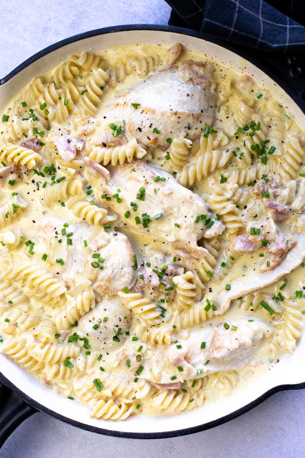 a skillet filled with pasta and chicken covered in sauce