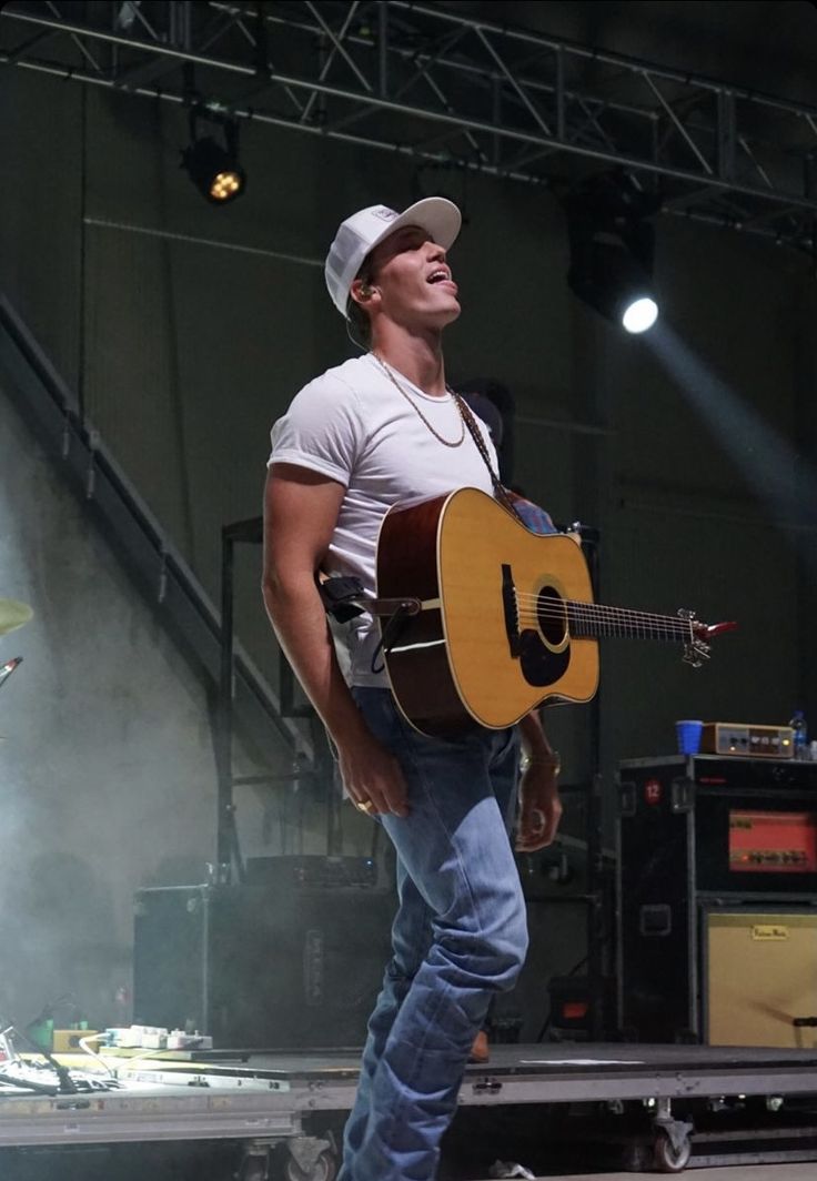 a man with a guitar standing on stage