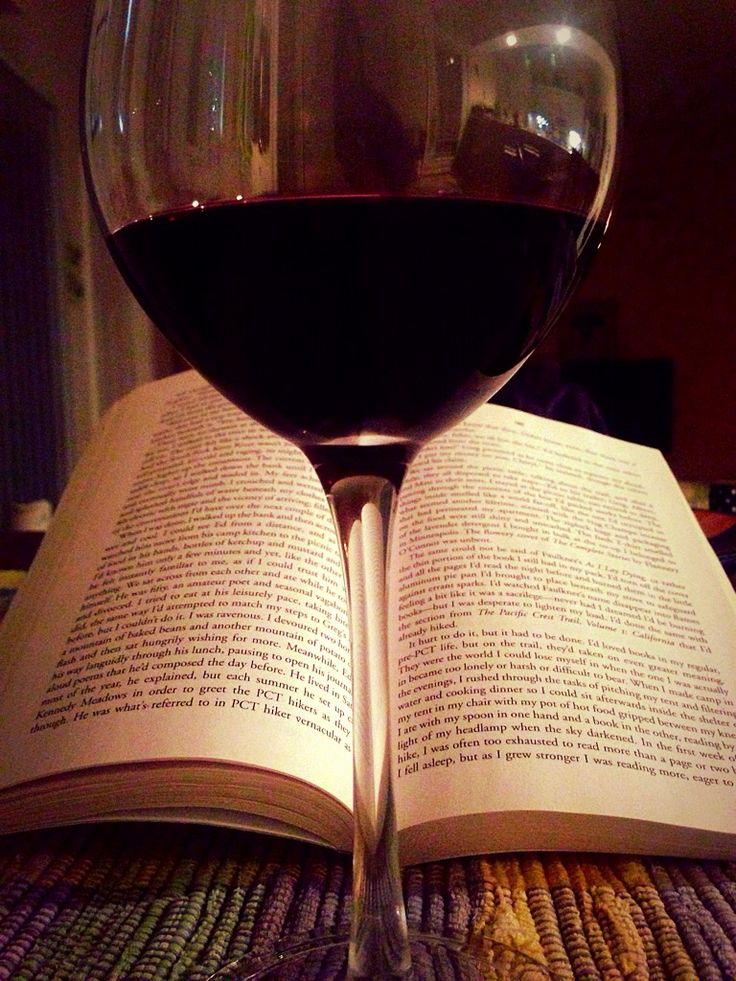 an open book and a glass of wine on a table