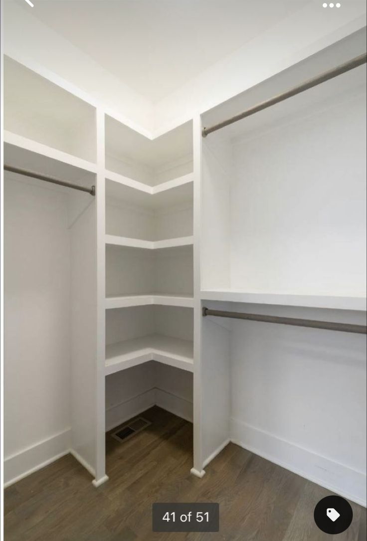 an empty walk in closet with white shelving and wood flooring on the walls