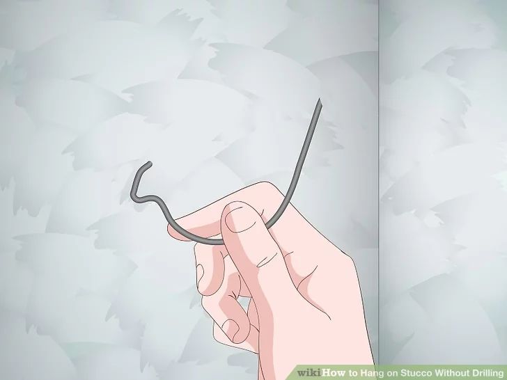 a hand holding a pair of scissors in front of a wall