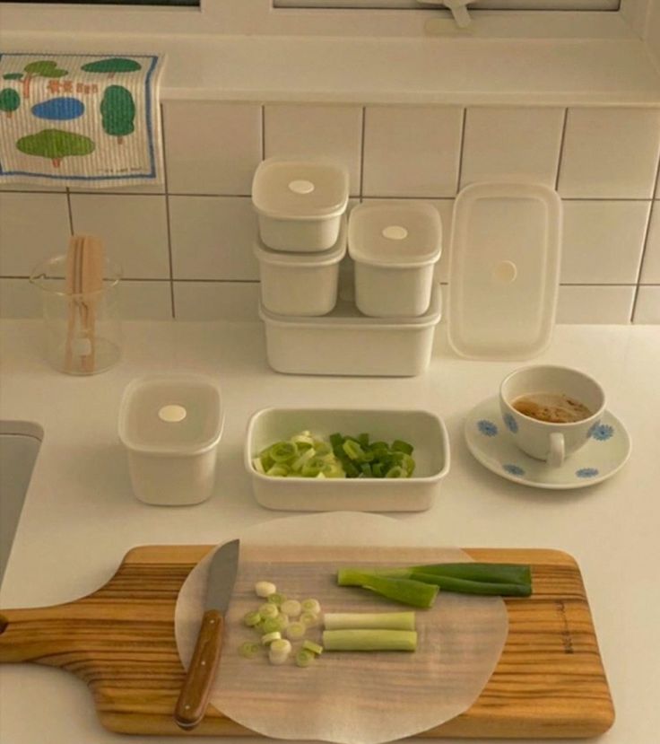 a cutting board with chopped celery on it next to two bowls and a knife