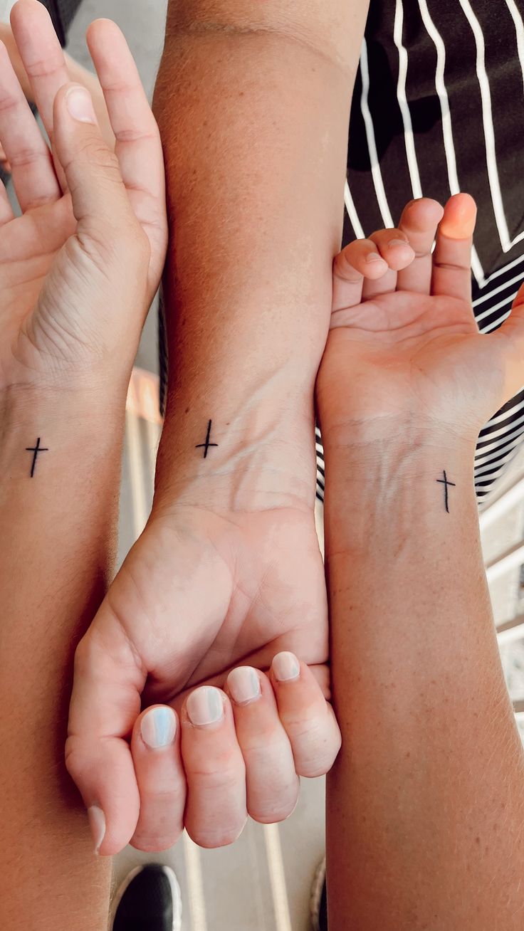 two people are holding their hands together with cross tattoos on the wrists and wristbands