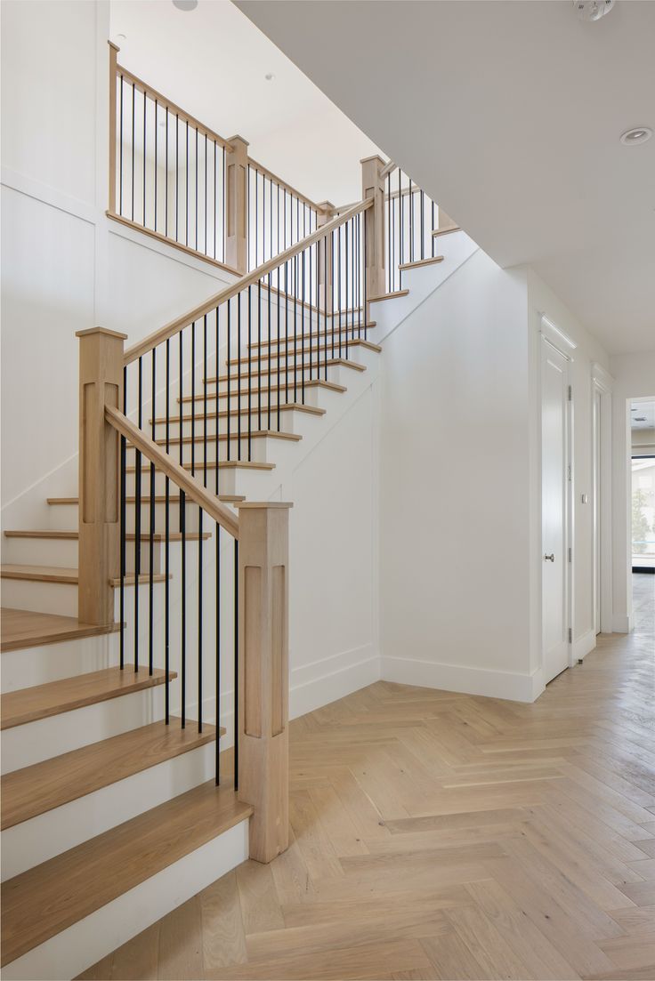 an empty room with wood floors and white walls has a staircase leading to the second floor