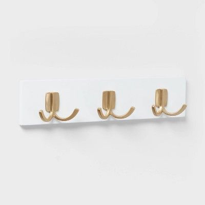 three gold hooks mounted on a white wall