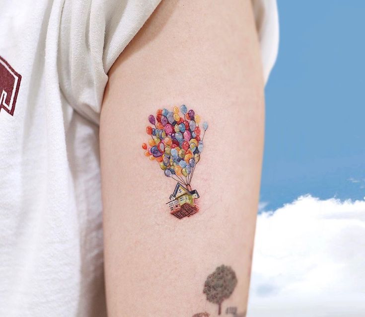 a person with a tattoo on their arm holding a candy bar hot air balloon in the sky