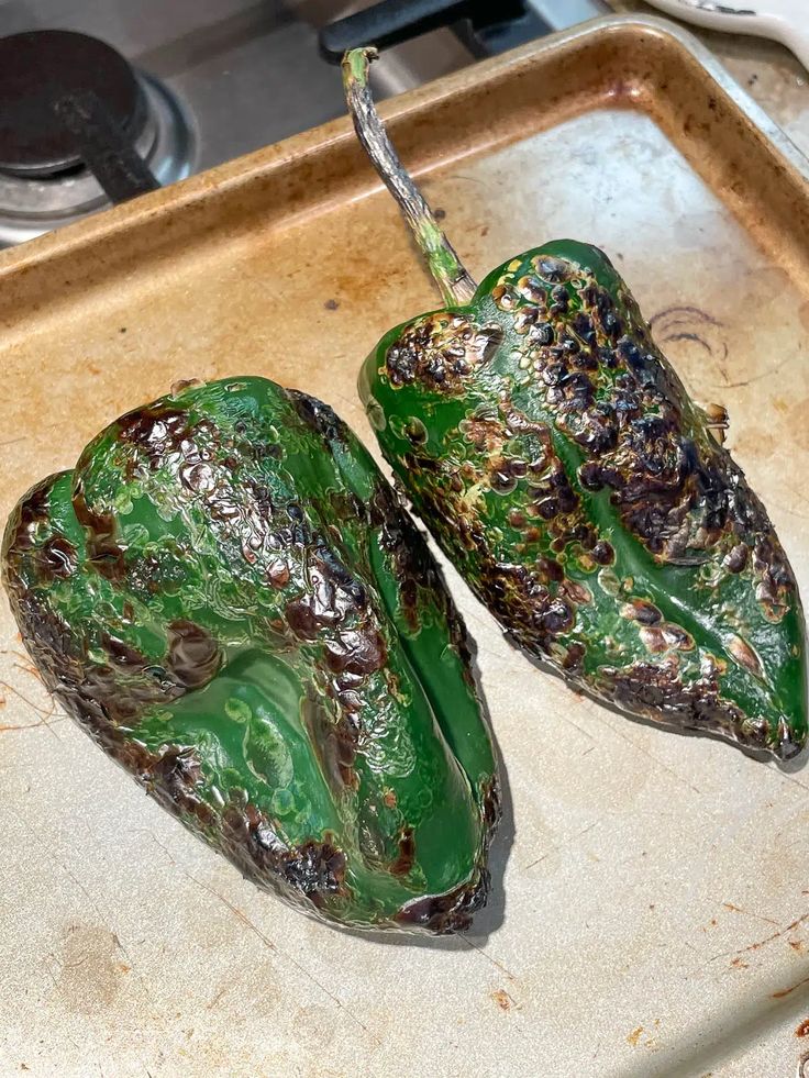 two green peppers sitting on top of a counter