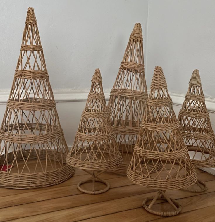 three wicker christmas trees sitting on top of a wooden floor