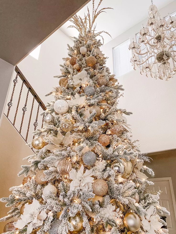 a white christmas tree with gold and silver ornaments