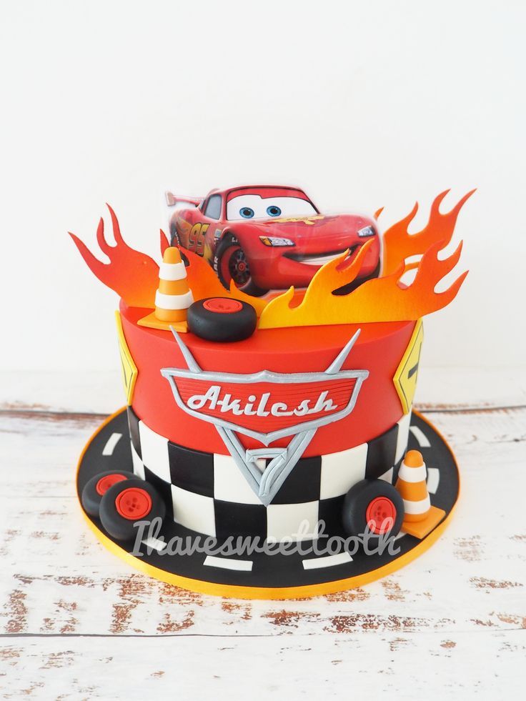 a birthday cake with cars on it and flames coming out of the car's hood