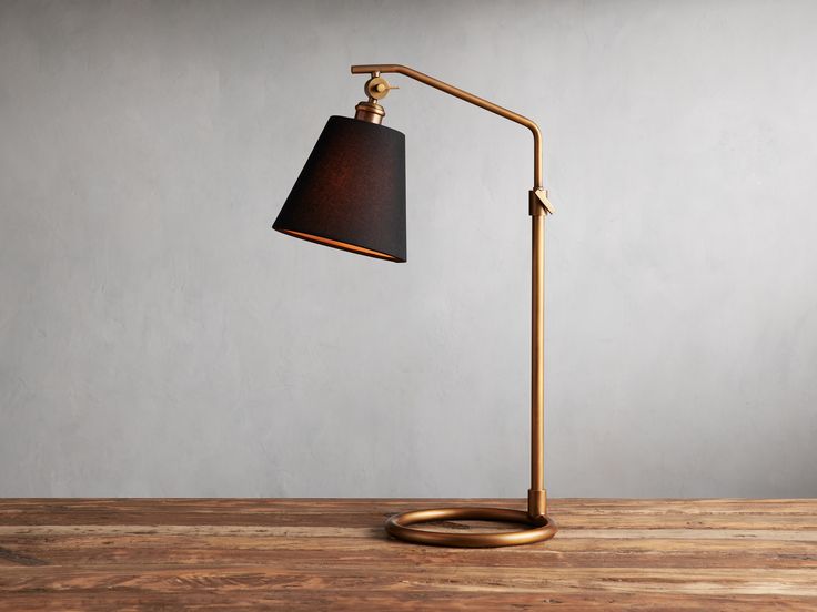 a desk lamp sitting on top of a wooden table next to a gray wall and floor