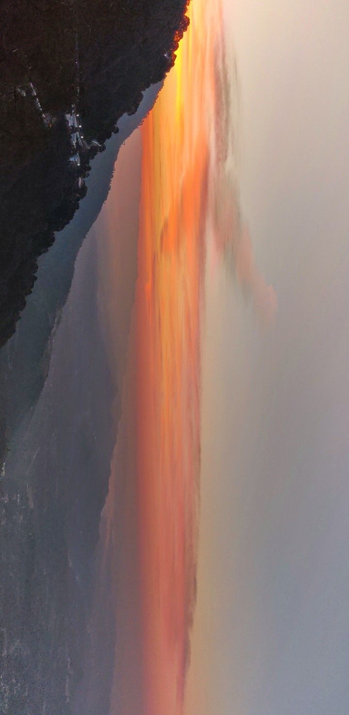 an aerial view of a waterfall in the middle of water with orange and yellow colors