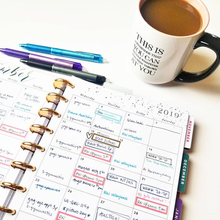 a cup of coffee sitting on top of a desk next to a planner