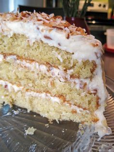 a piece of cake with white frosting and nuts on top is sitting on a glass plate