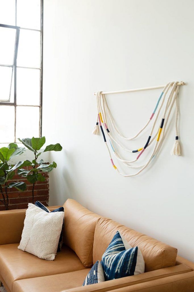 a brown leather couch sitting in front of a window next to a potted plant