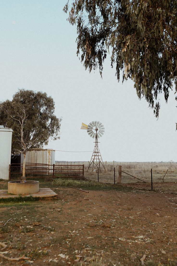 an old farm with a windmill in the distance