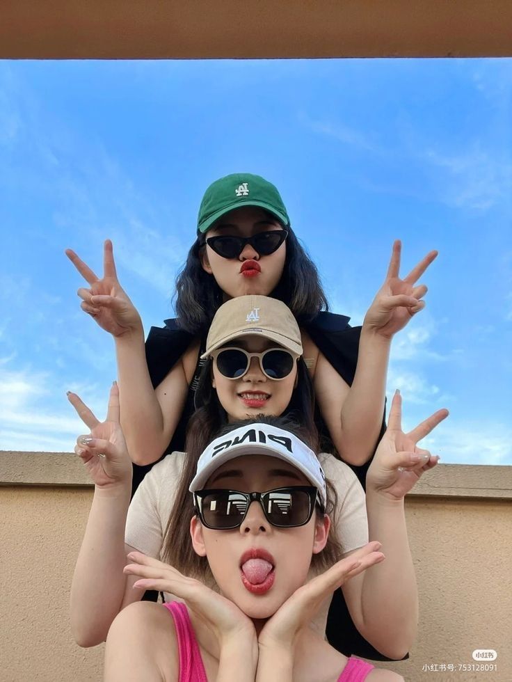 three girls with their hands up in the air and one girl wearing sunglasses on her head