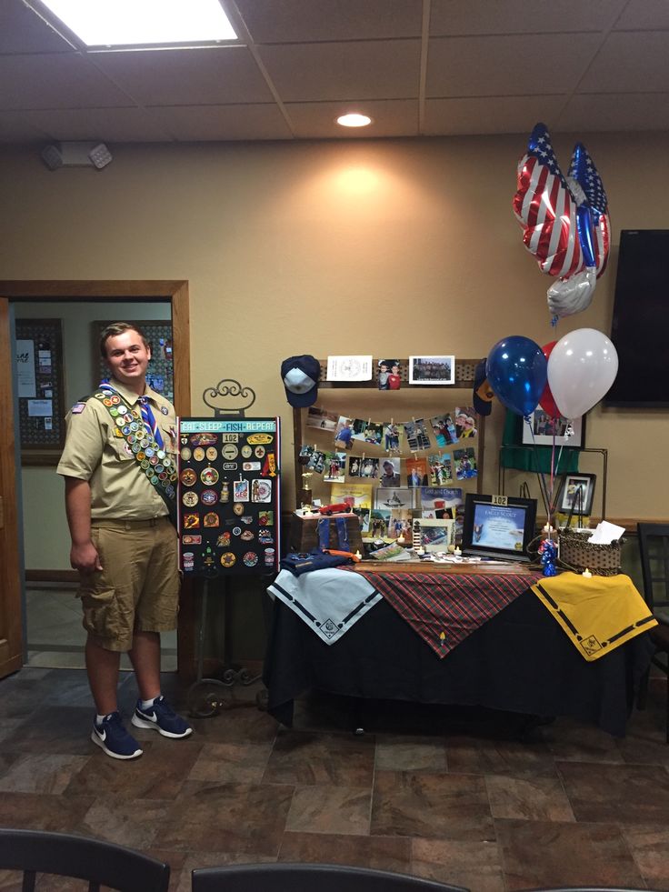 a man standing in front of a table with balloons and pictures on the wall behind him