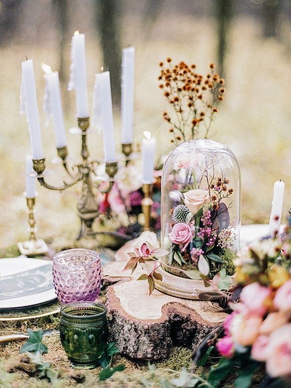 a table topped with candles and flowers under a cloche dome