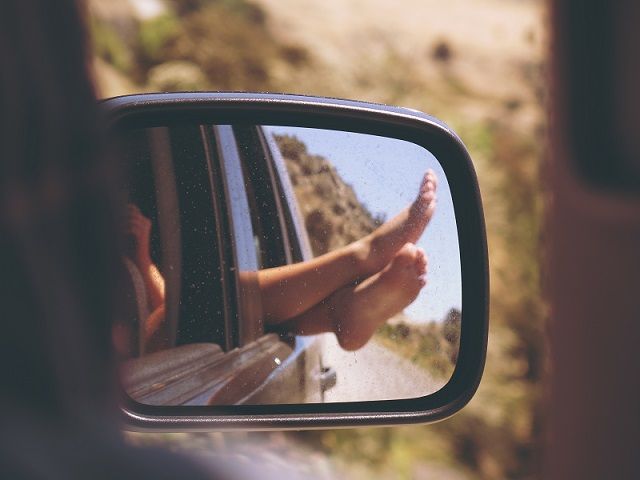 a person's reflection in the side view mirror of a car