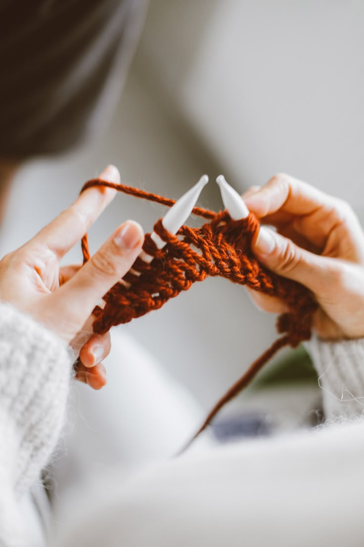 a woman is knitting something with her hands