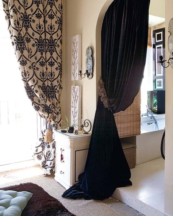 a bedroom with black drapes on the windowsill and curtains hanging from the ceiling