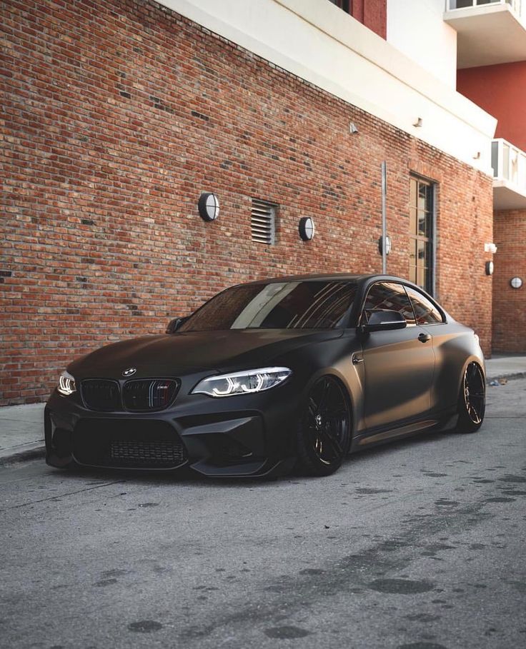 a black car parked in front of a brick building