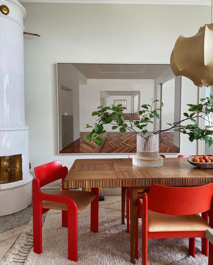 a dining room table with red chairs and a potted plant