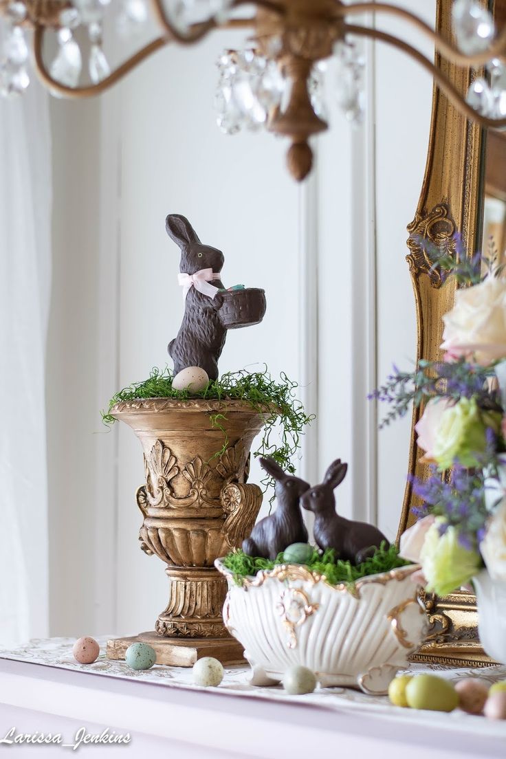 two rabbits sitting on top of a potted planter next to an ornate mirror