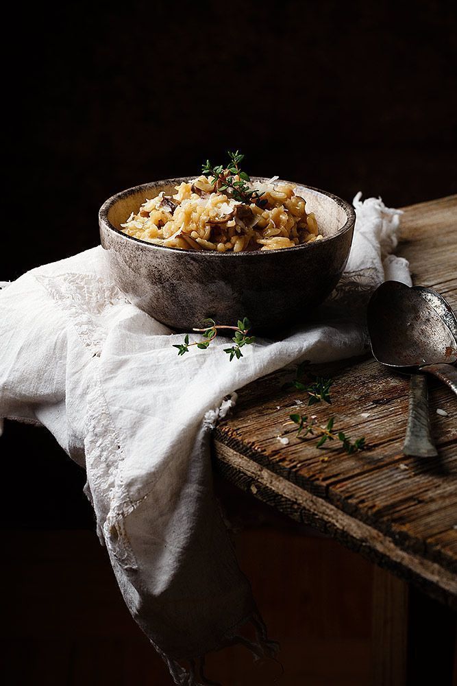 a bowl filled with food sitting on top of a wooden table next to a spoon