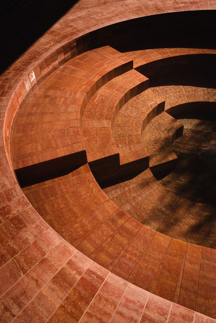 an aerial view of a circular brick structure with steps in the center and a clock on top