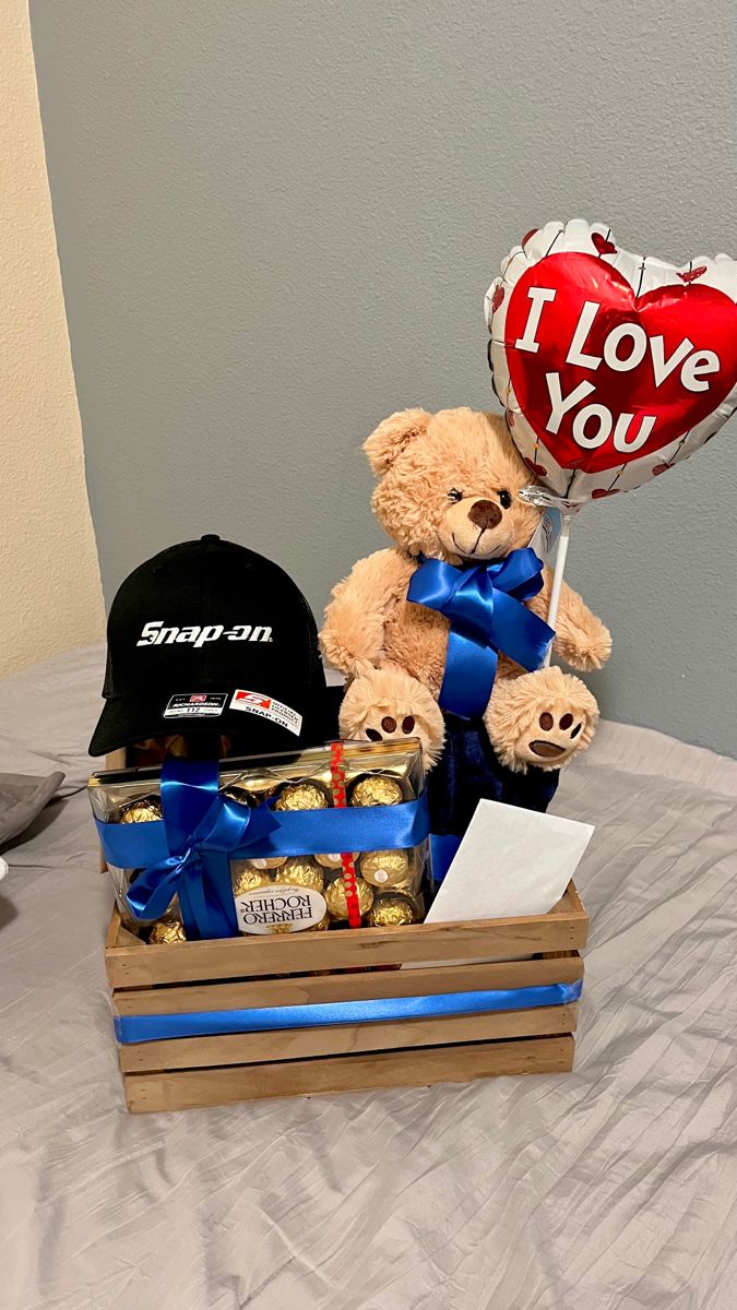 a teddy bear sitting on top of a bed next to a heart shaped balloon