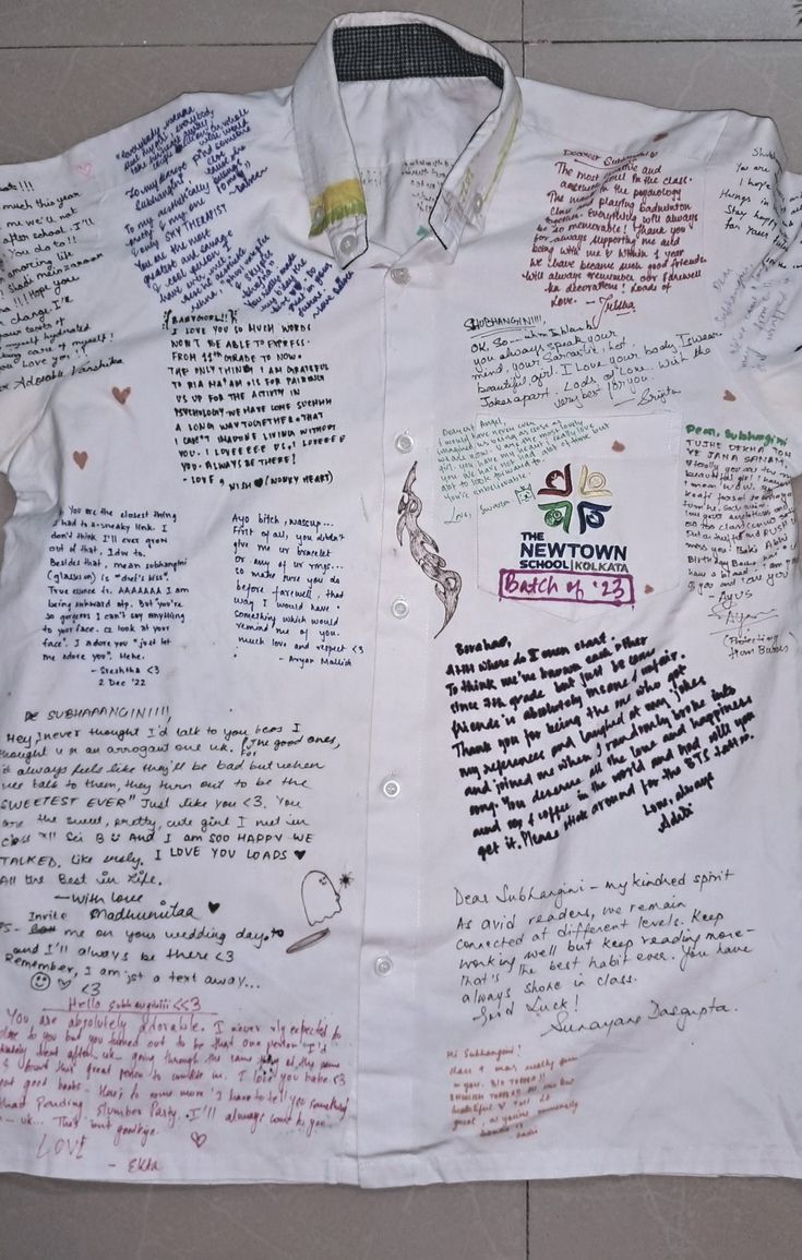 a white shirt with writing on it sitting on top of a tile floor next to a wall