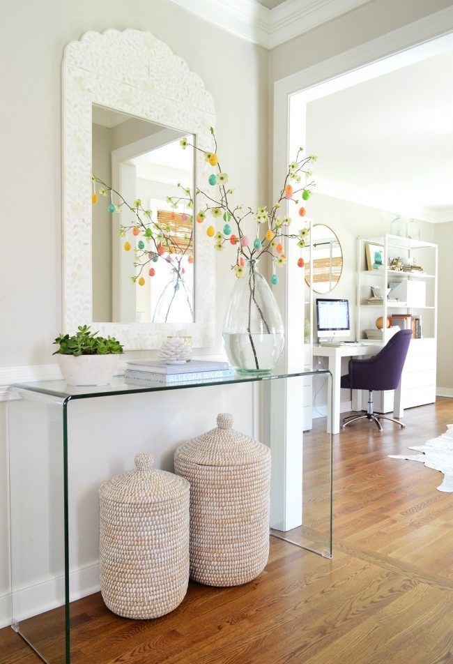 a glass table with two baskets underneath it and a mirror on the wall behind it