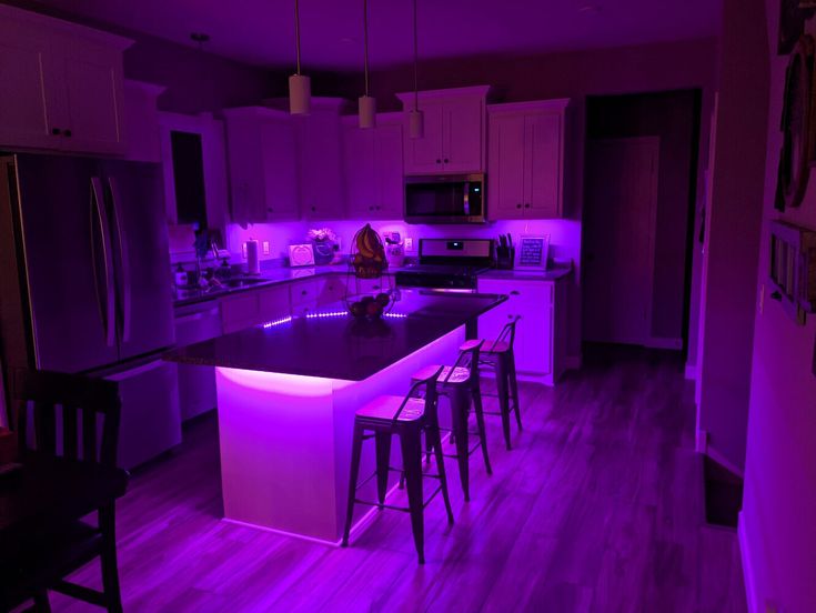 a kitchen with an island and purple lighting