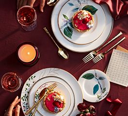 two white plates topped with food on top of a table next to candles and napkins